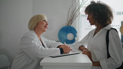 smiling nurse talking client at reception desk closeup.patient visit clinic
