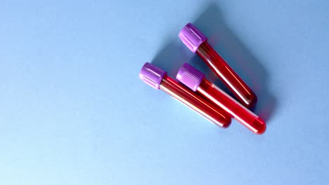 Close-up-of-blood-samples-on-blue-background-with-copy-space,-slow-motion