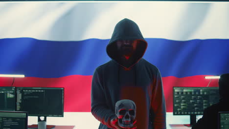 digital outlaw hacker in a dark hood issuing cyber threats with a human skull