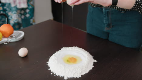 woman prepares sweet dough with flour and fresh chicken eggs
