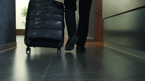 businessman walking with luggage in hotel corridor