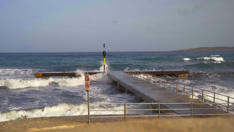 ocean waves breaking at a stone peer on mallorca with big splashes