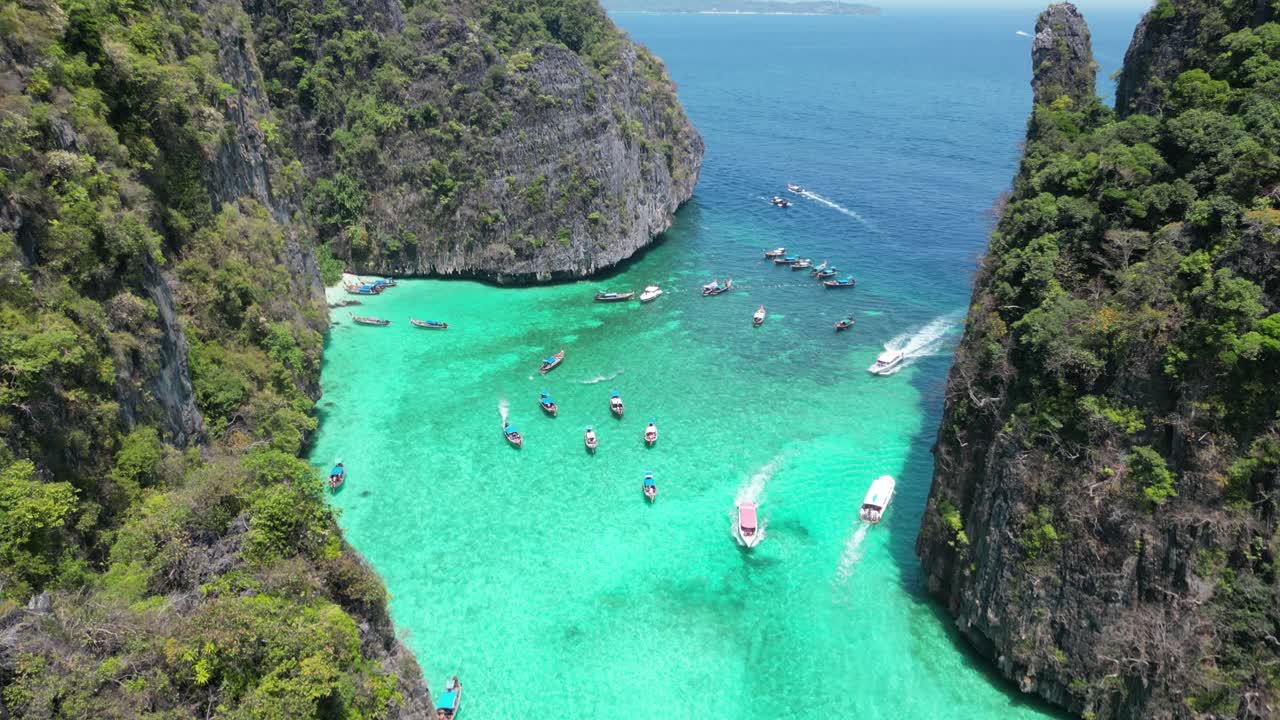 Cảnh quay drone tiến về phía trước trên Đầm Pileh với góc nhìn hơi từ trên xuống, tiết lộ làn nước màu ngọc bích, vách đá vôi dốc đứng và thuyền du lịch tham quan trong một vịnh nhiệt đới kín gió vào một ngày nắng đẹp