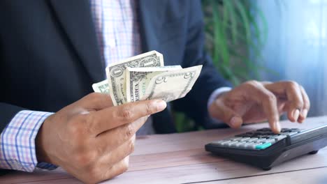 businessman counting money and using a calculator