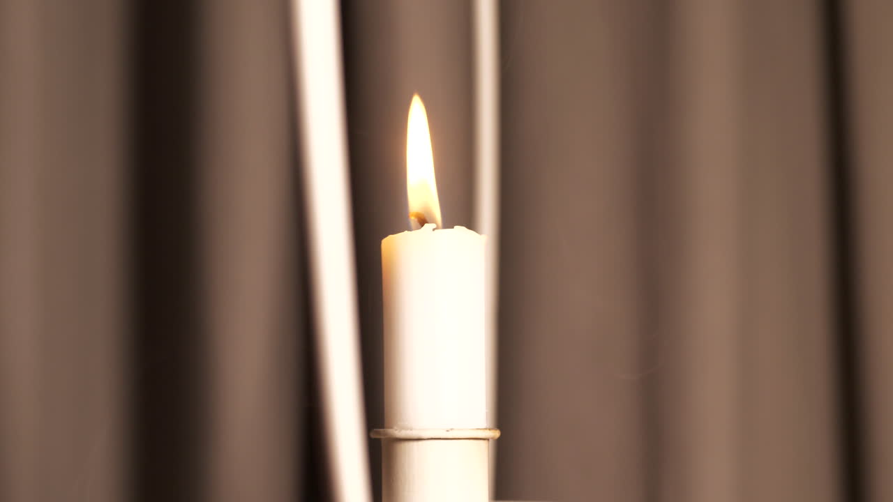 Primo piano del fumo che sale da una candela in movimento con tende sullo sfondo.