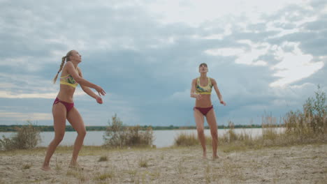 los jugadores de voleibol de playa están entrenando al aire libre dos mujeres deportistas están pasando y atacando la cámara lenta