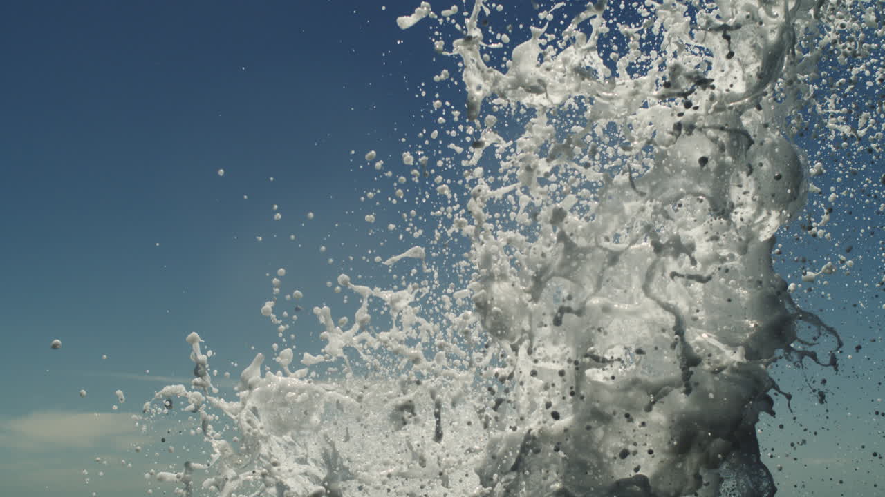 Skyward spray from ocean blowhole erupts in slow motion over dark sea horizon line