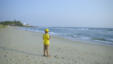 niño volando un dron en el lado de la playa