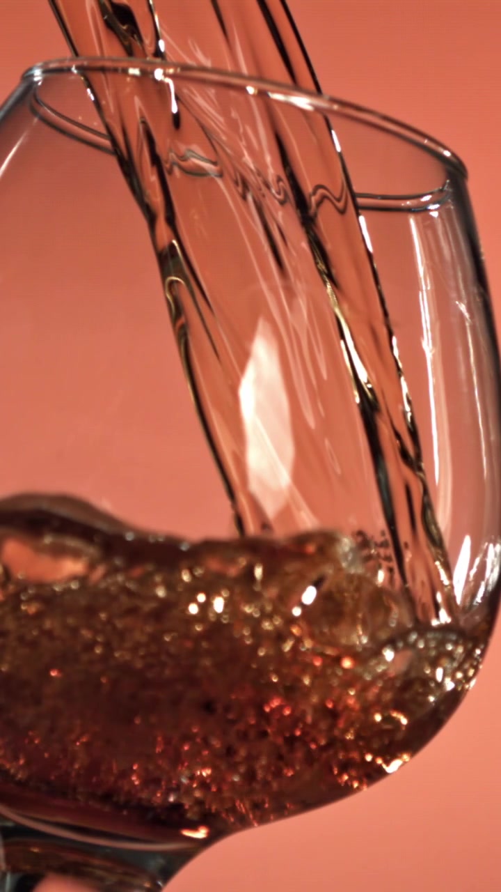 Versamento di liquido dorato in un calice snifter al rallentatore