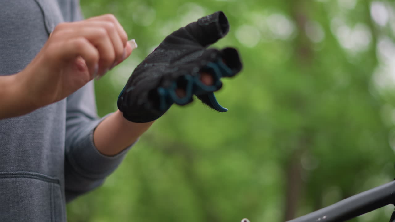 Person Finetuning Riding Gloves In Nature, Close Perspective Of Individual Wearing Cycling Gloves Amidst Woods, Detailed Image Of Cyclist Putting On Gloves Surrounded By Natural Woodland Scenery