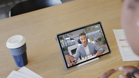 caucasian businesswoman on tablet video call with caucasian male colleague on screen