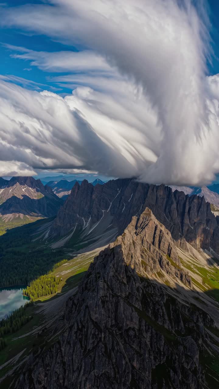 Aerial view of dramatic cloud formation over jagged mountains, creating a dynamic and cinematic