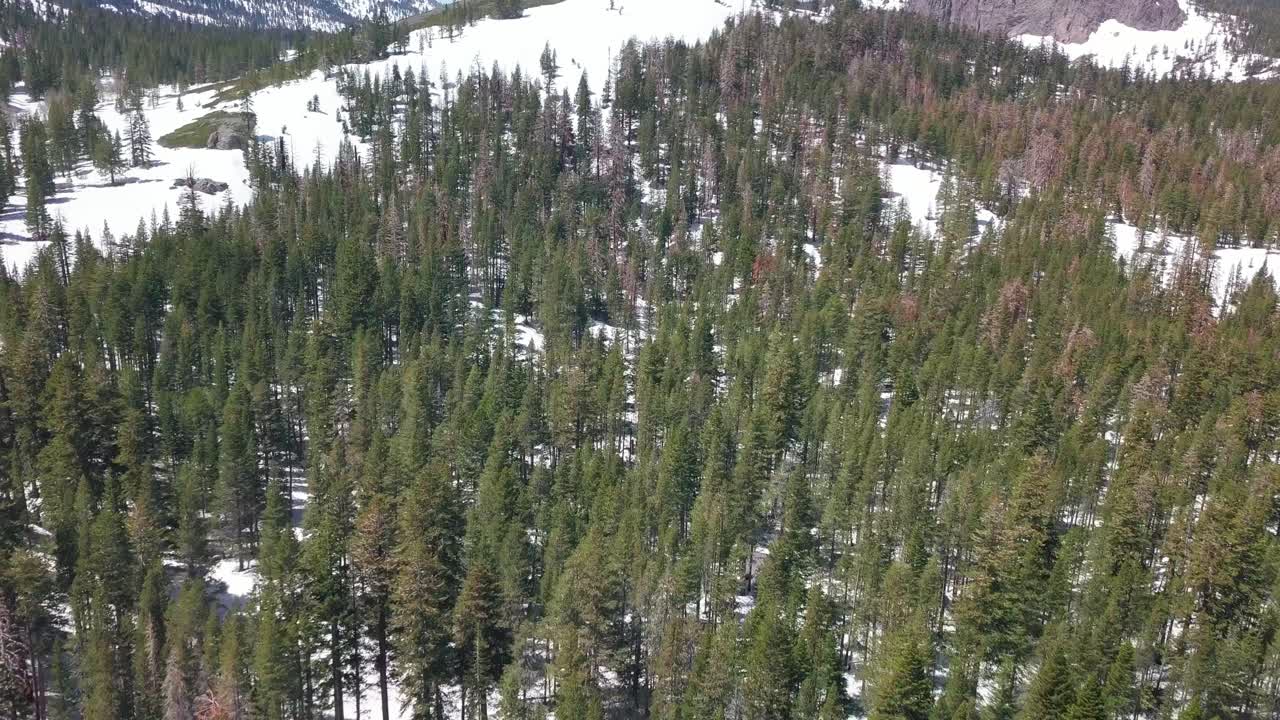 vuelo aéreo de empuje hacia una colina cubierta de nieve con altos picos montañosos al fondo