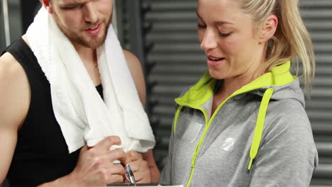 un hombre musculoso discutiendo con una atleta.