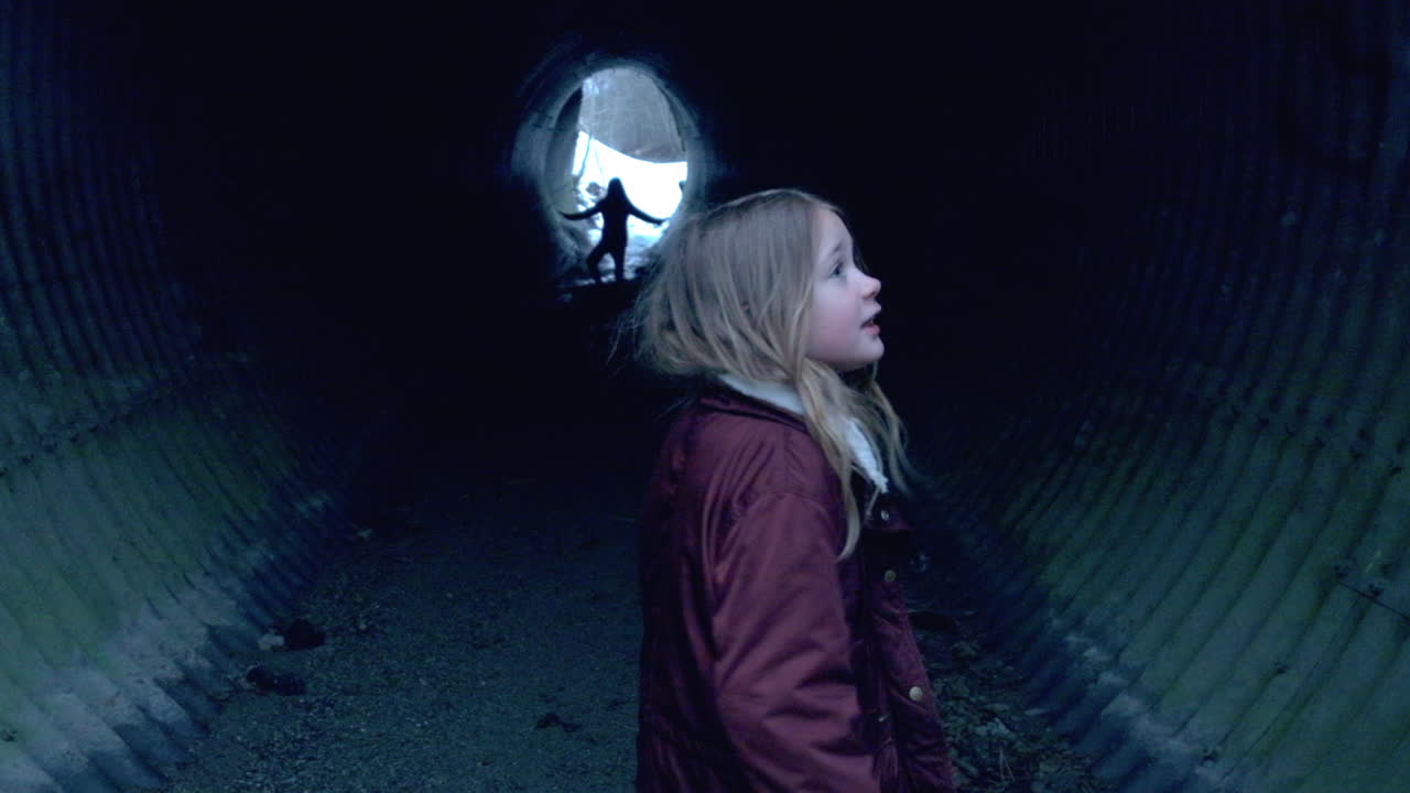 A little girl walking into a dark underground tunnel feeling scared