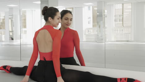 ballerina does a split against mirror walls in a white dancing studio