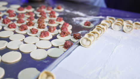 little white dough circles are filled with minced meat. semi-finished ravioli on the metal table in the cooking process. close up.