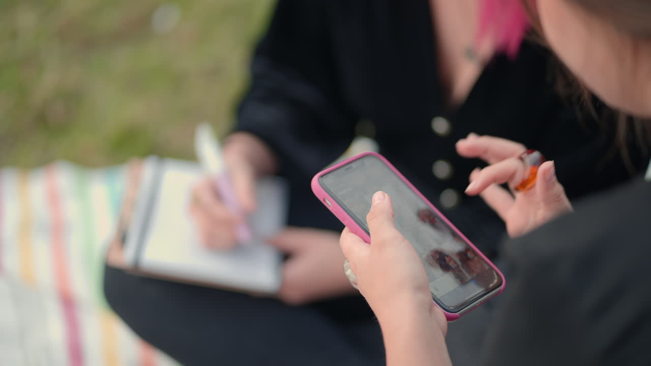 Two women using smartphones outdoors