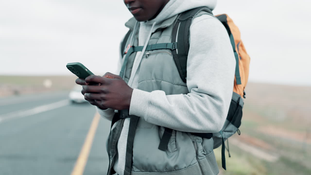 Man with Backpack Using Smartphone on Road