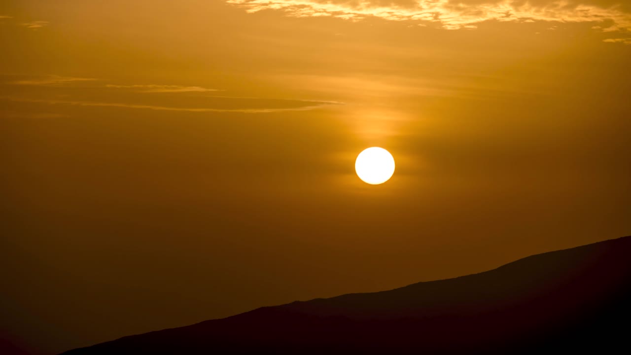 vista de cerca del sol al amanecer con una cresta montañosa en primer plano, madeira, portugal