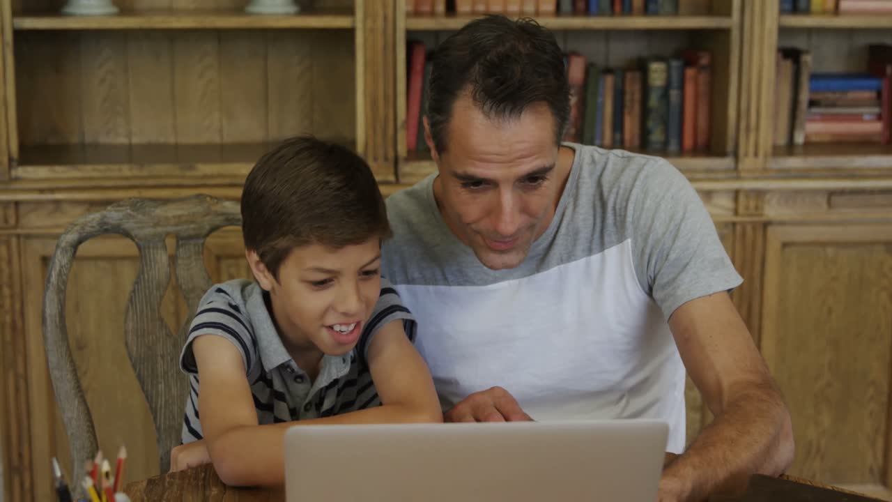 padre e hijo usando una computadora portátil en la sala de estudio