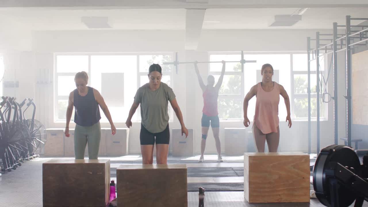 mujeres diversas decididas inalteradas saltando en cajas, entrenando en clase de gimnasia en gimnasio, cámara lenta