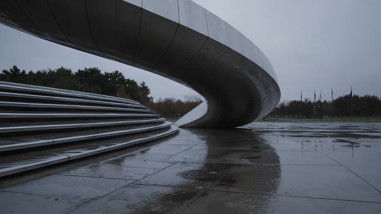 Modern Curved Metallic Sculpture on a Wet Urban Plaza