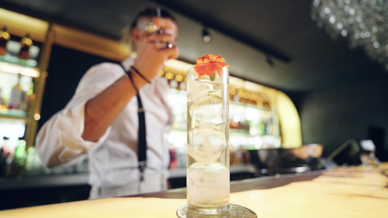 Barman che guarnisce un cocktail rinfrescante con un fiore in un bar