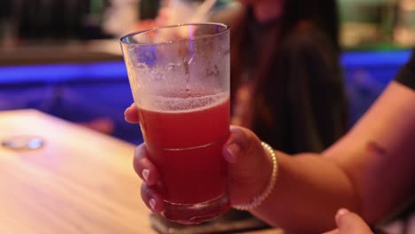 persona sosteniendo una bebida roja en un bar