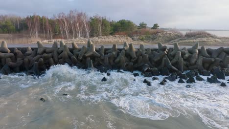 aerial establishing view of port of liepaja concrete pier, baltic sea coastline day, big waves splashing, slow motion drone dolly shot moving right