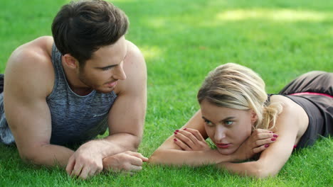 sport people relaxing after outdoor training. man and woman lying on green grass