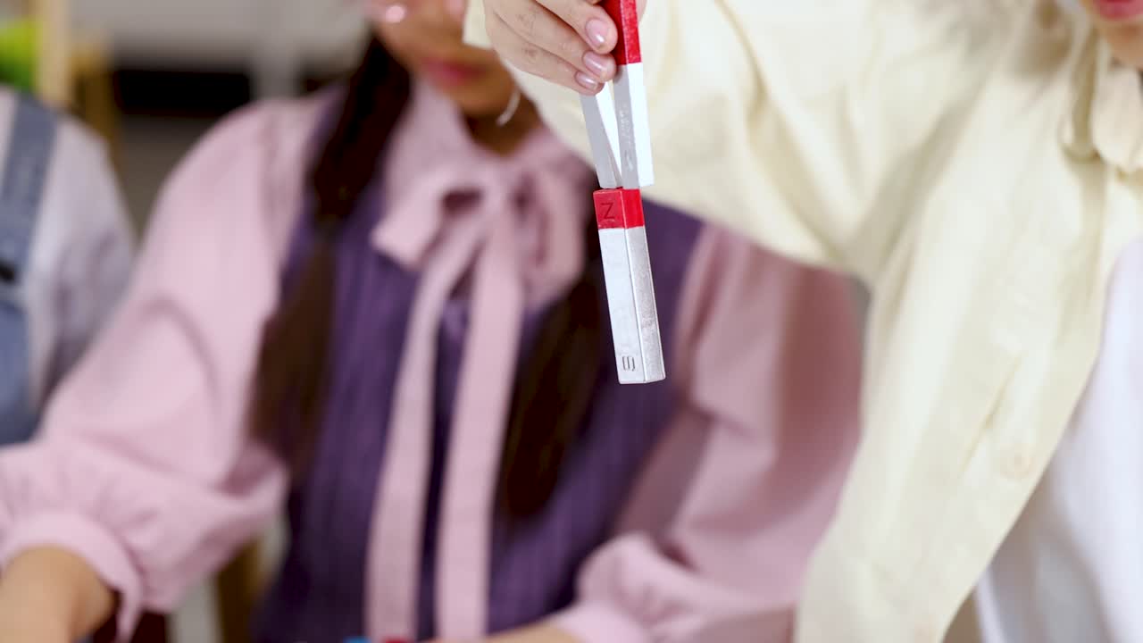 Close up shot of students conducting a science experiment with magnets on a white table