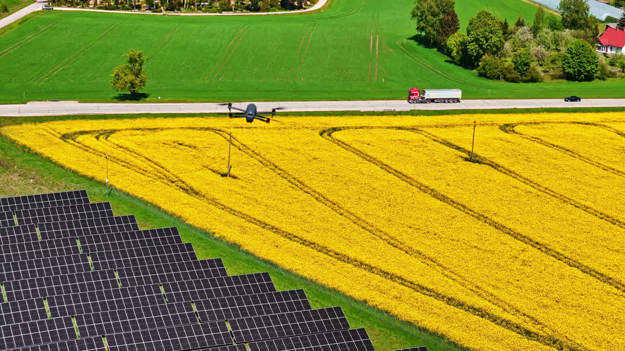 Drone flying over yellow farmland with solar panels and a truck on a rural road