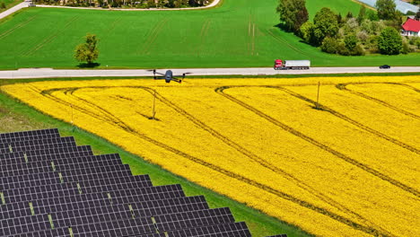 drone flying over yellow farmland with solar panels and a truck on a rural road