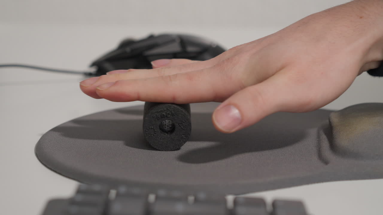 Man massaging his hand with a foam roller on a mouse pad