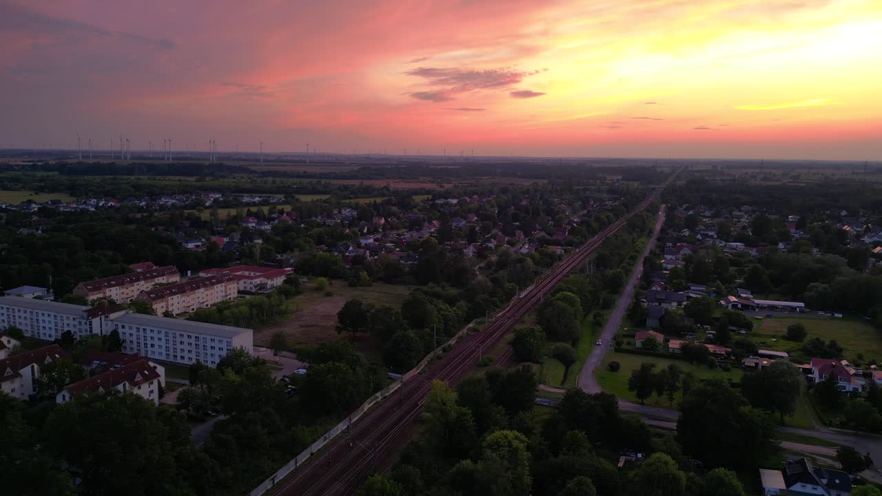 저녁에 작은 마을과 숲을 가로질러 철도에서 여행하는 여객 열차. 환상적인 공중 전망 비행 파노라마 개요 드론