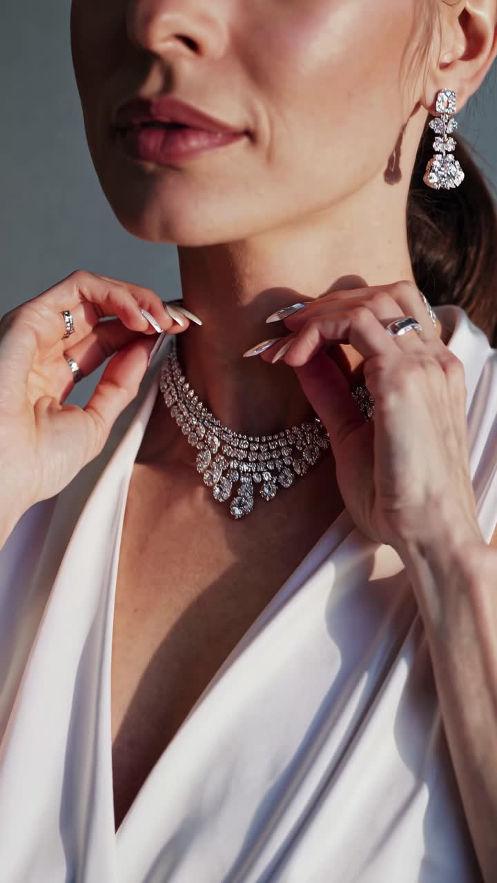 Close-up video shot of a woman adjusting her diamond necklace and earrings, highlighting elegance