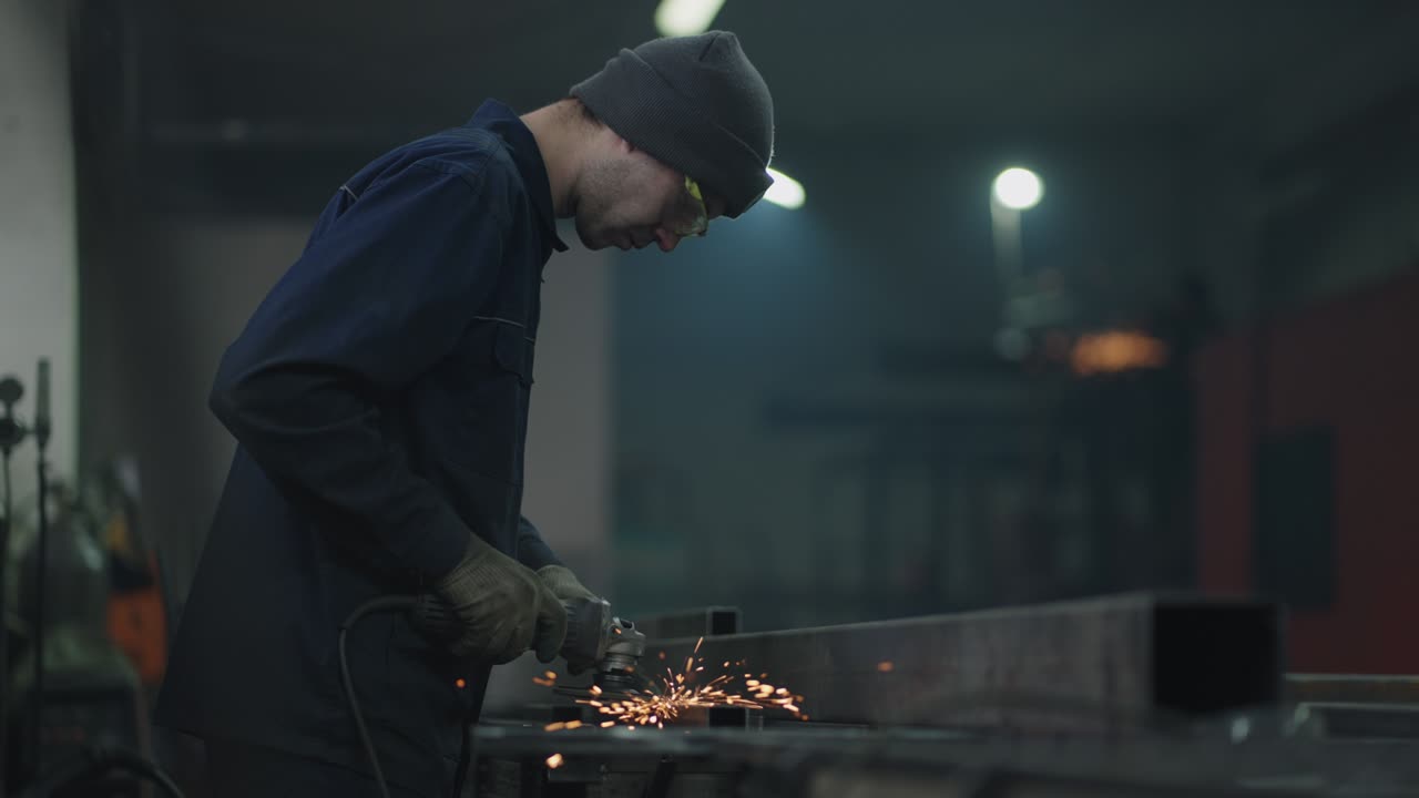Ripresa dal basso: Un uomo con occhiali protettivi lavora il metallo levigando, lucidando e sverniciando strutture metalliche in acciaio
