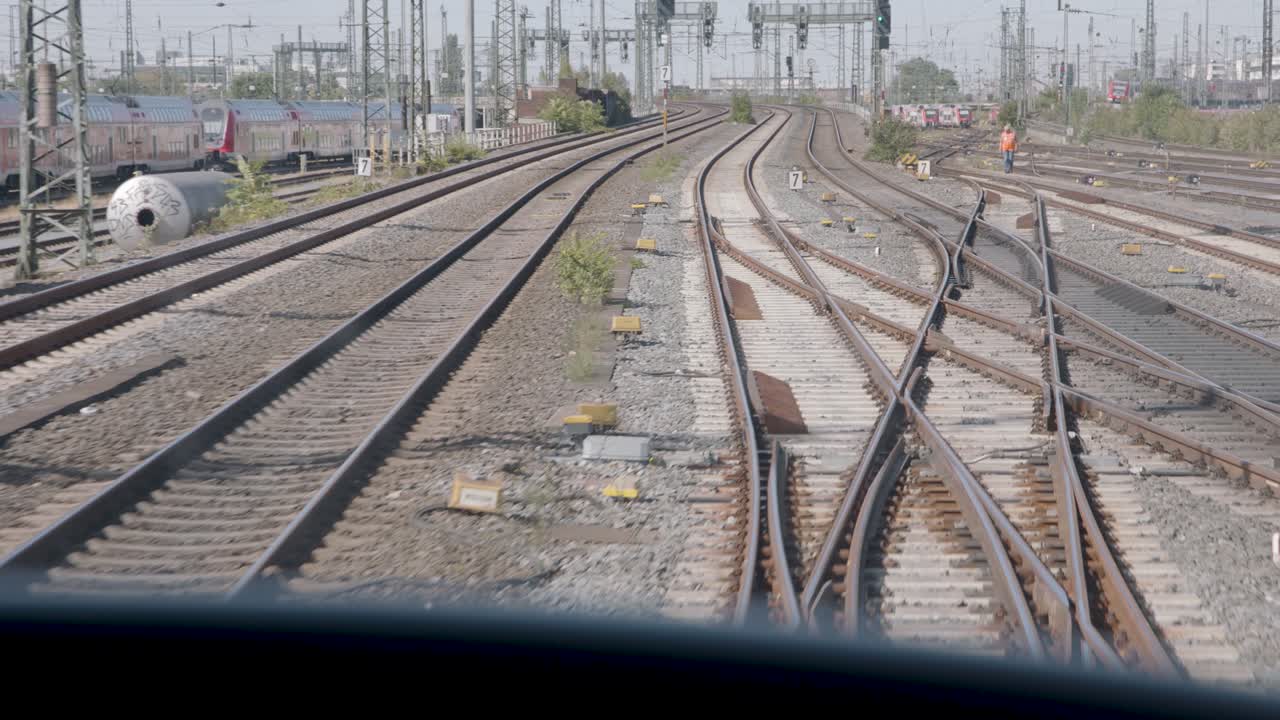 View of multiple railway tracks splitting at a busy train station in bright daylight