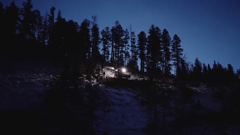 wide, far away establishing shot of nighttime industrial wood logging operation machinery moving around