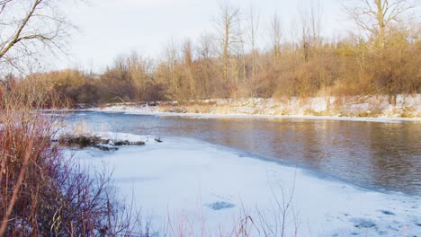 wide shot of a flowing river with ice forming