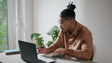 modern student learning remotely closeup. stylish guy making notes at home alone