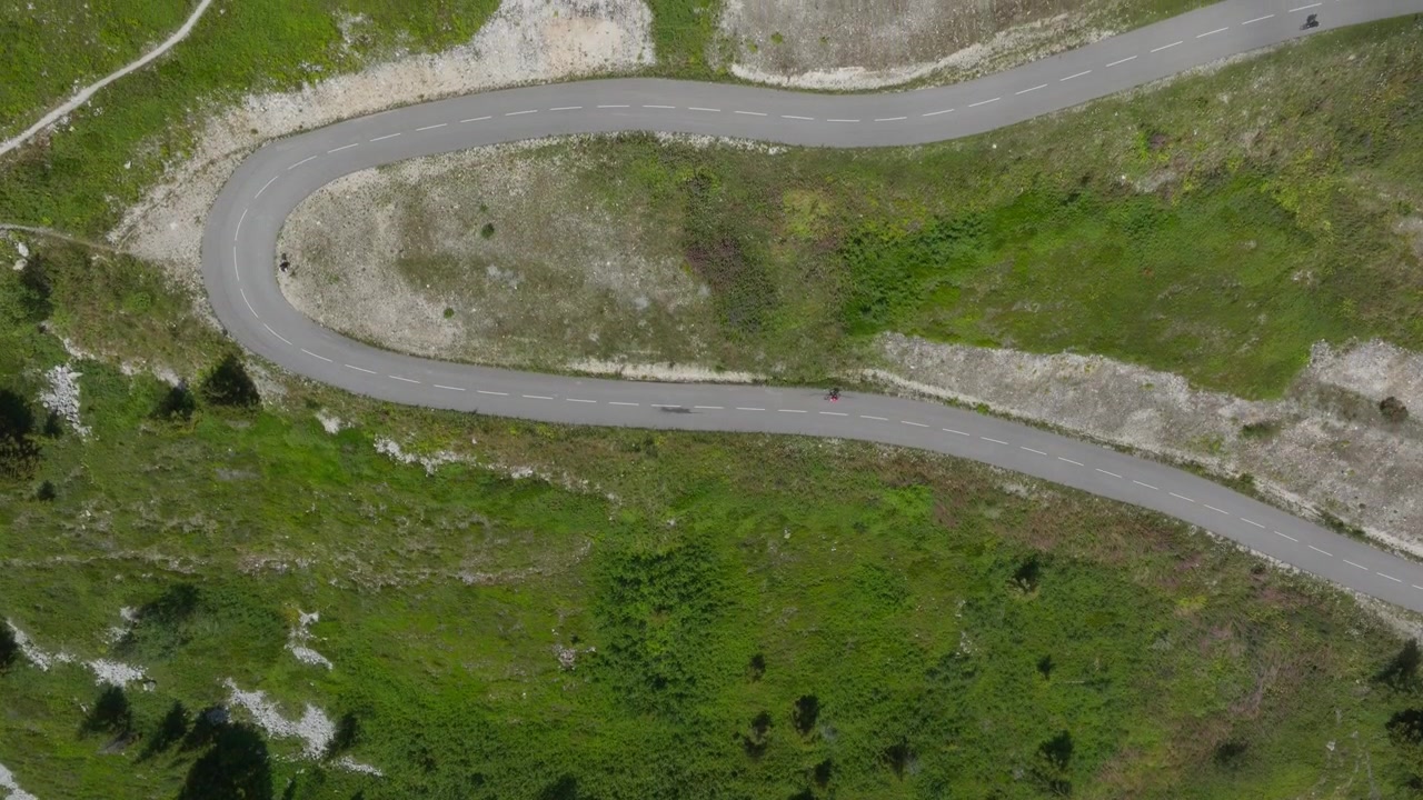 Riprese aeree cinematografiche con drone delle Alpi francesi che mostrano paesaggi montani mozzafiato, strade alpine tortuose, rigogliose valli verdi e ciclisti che attraversano scenari spettacolari. Perfetto per i viaggi.