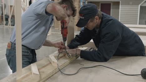 trade school carpentry workshop instructor assists student with building a staircase