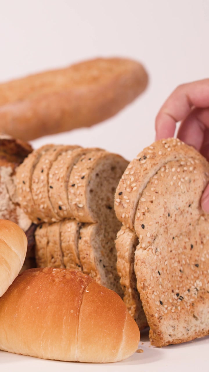 Una mano seleziona una fetta di pane ai cereali da un assortimento di prodotti da forno freschi