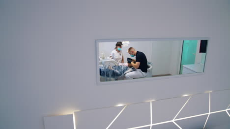 treatment of teeth in dental office. stomatologist man and female assistant working in a modern dental cabinet. dental health. view from the small window on dental procedure.