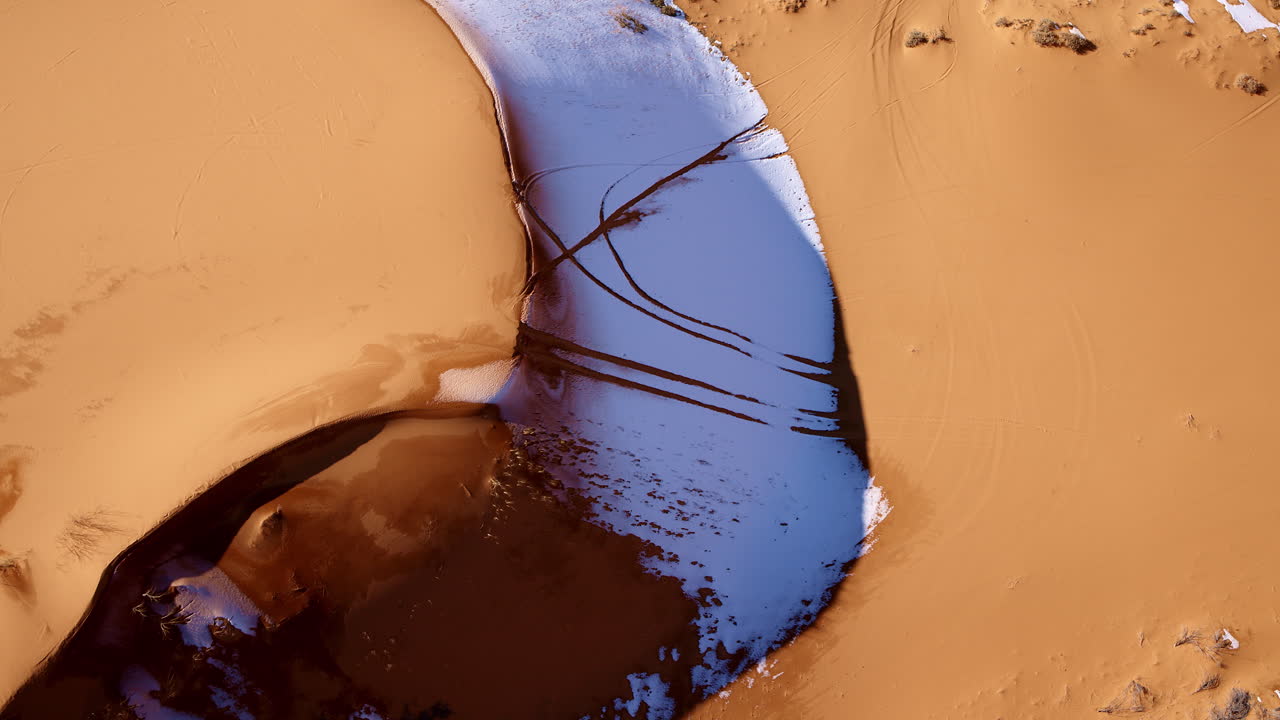 Aerial drone shot directly overhead reveals the vibrant, pink-toned dunes with fascinating formations.