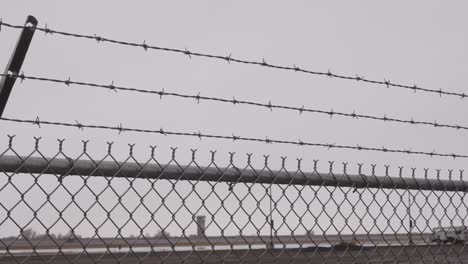 a barbed wire and chain link fence with an airport control tower in the background