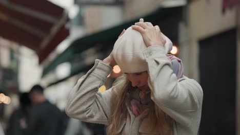 una joven feliz con su sombrero de boina de lana blanca con un fondo borroso de gente en la calle en italia