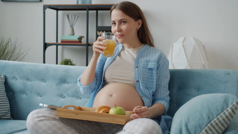 pregnant woman enjoying breakfast on the couch